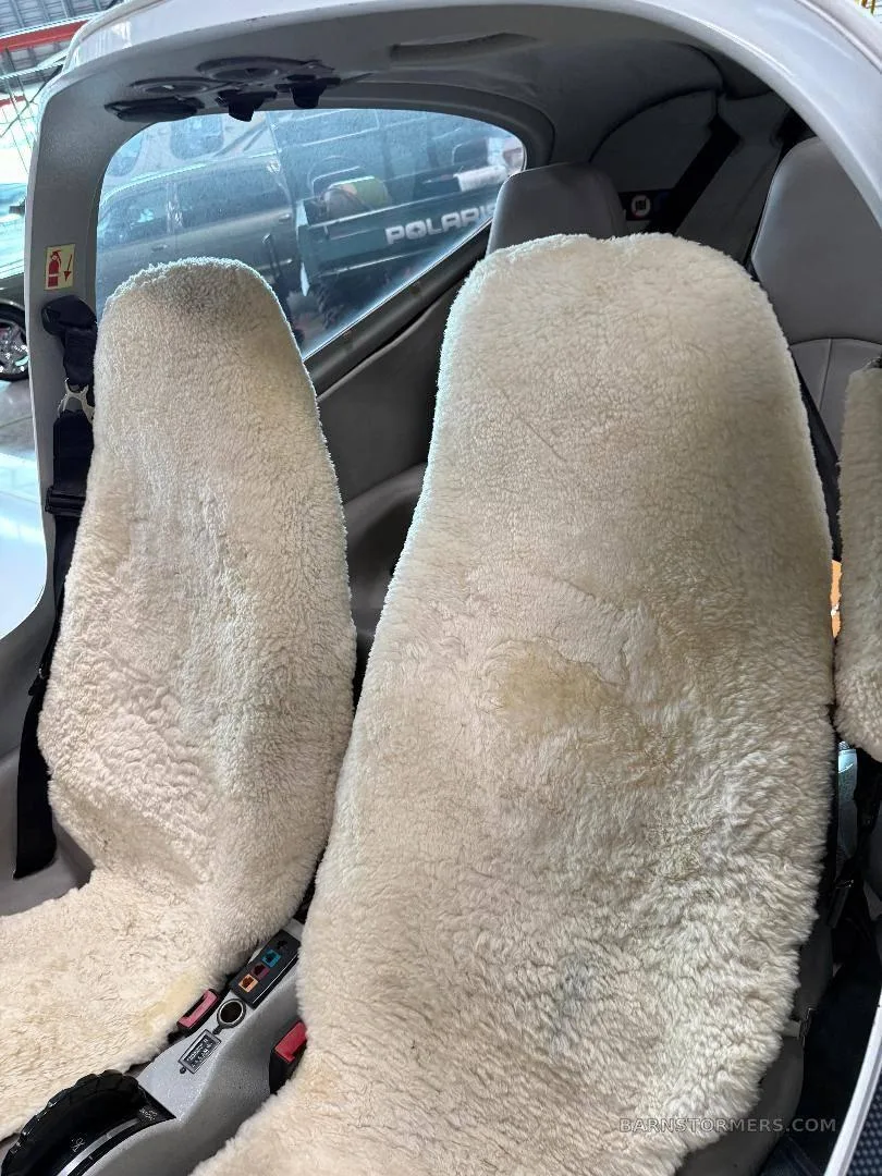 The front two seats of the aircraft cabin, covered with white sheepskin seat covers.