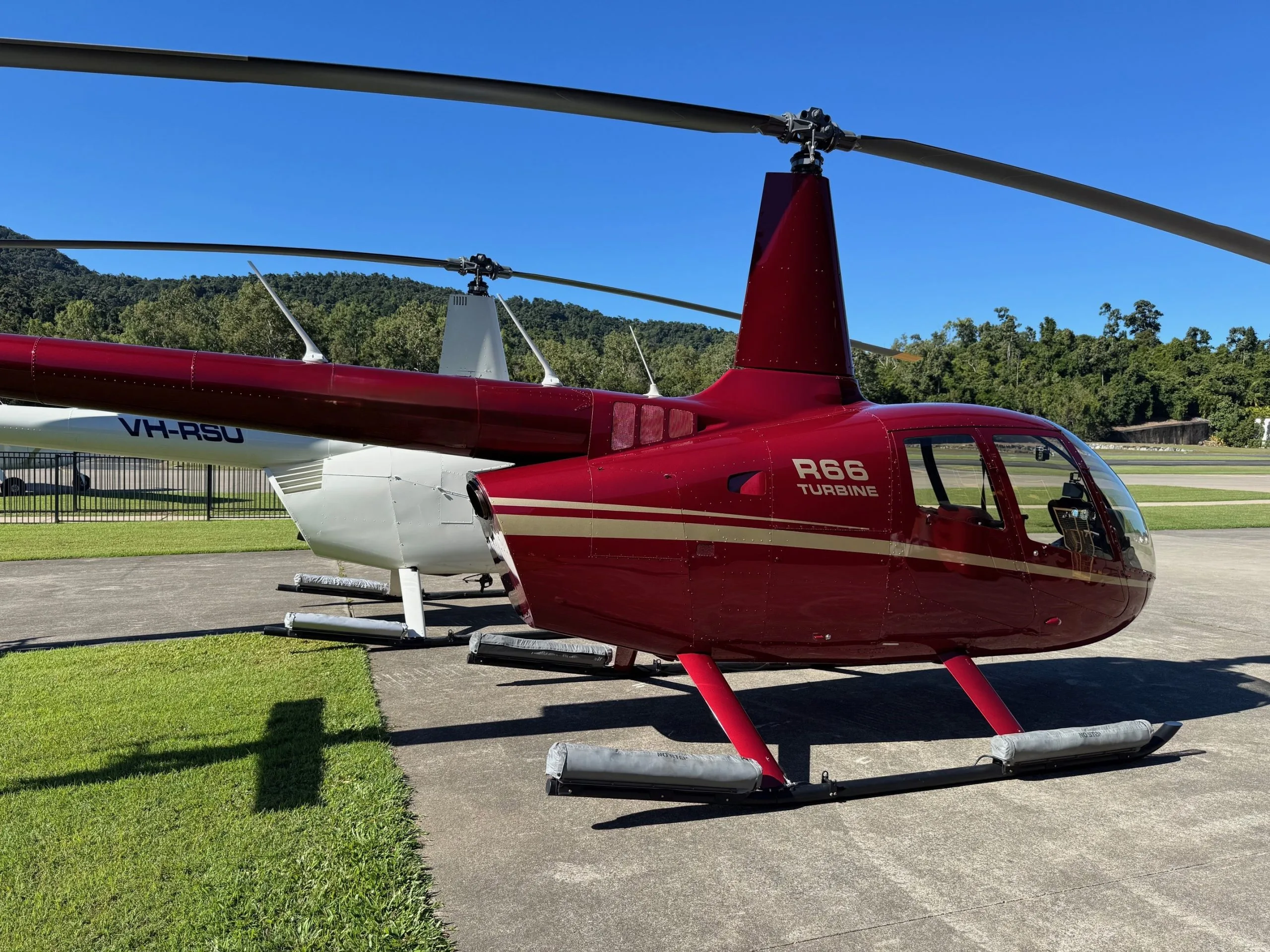 Maroon Robinson R66 Turbine helicopter parked on the tarmac.