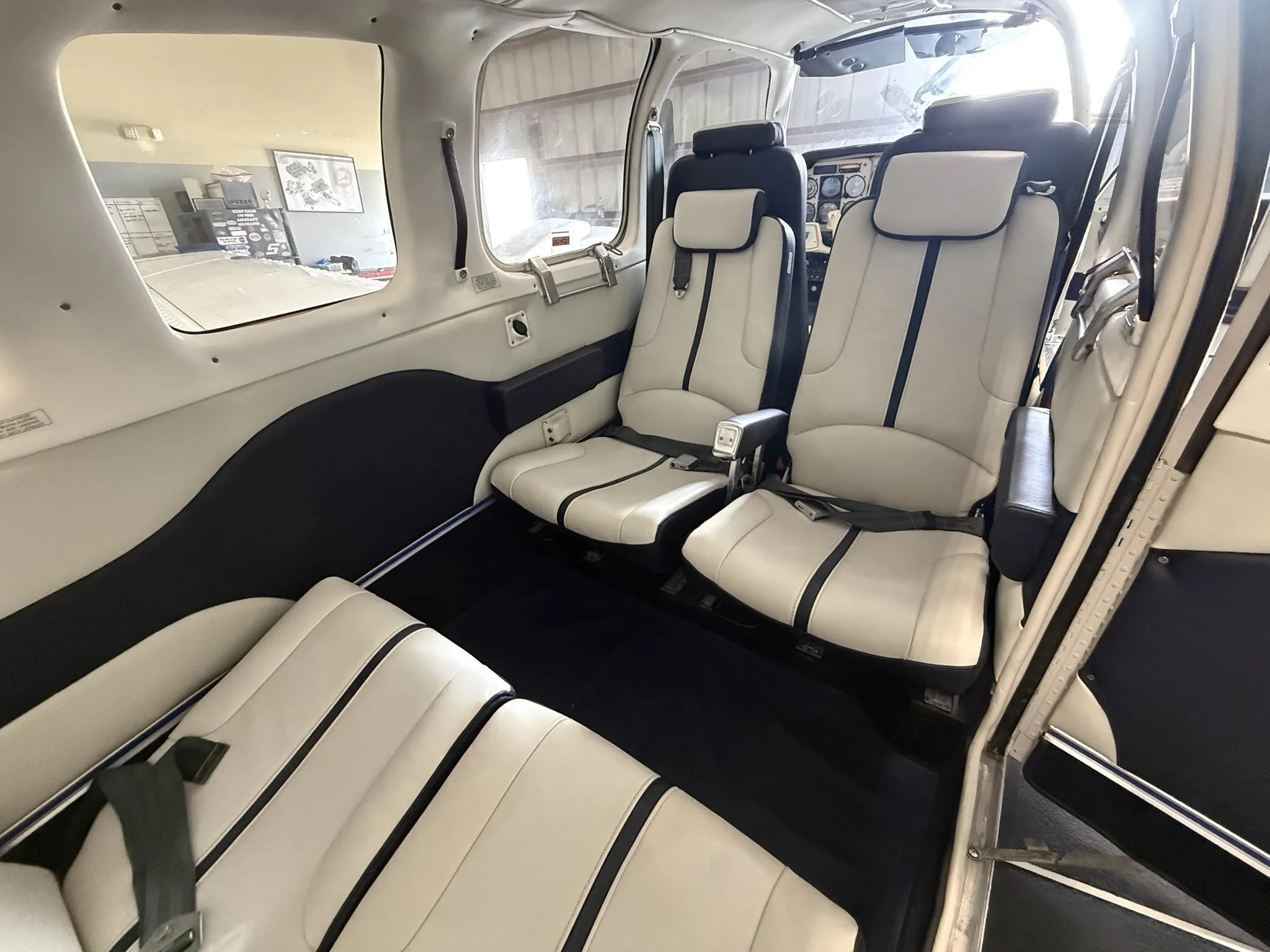 The aircraft's interior cabin showing white and blue leather passenger seats and a glimpse of the cockpit.