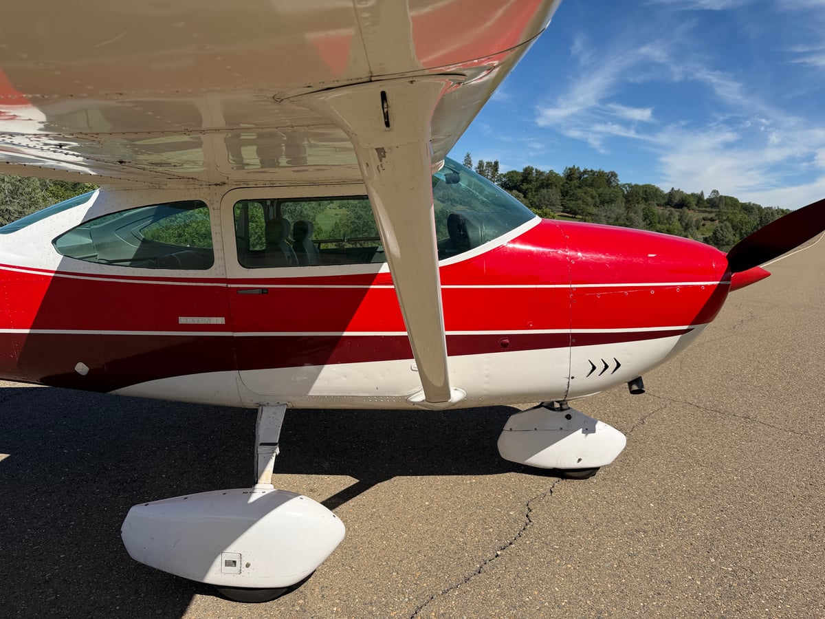 Close-up of the landing gear and lower fuselage of the red and white Cessna Skylane.
