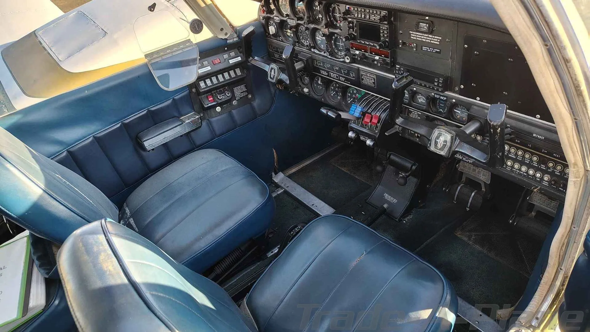 A wide view of the cockpit and front blue seats of a Piper PA-23-200.