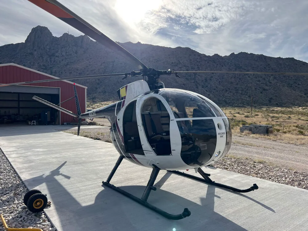 Another angle of the McDonnell Douglas 500C helicopter with mountains in the background.