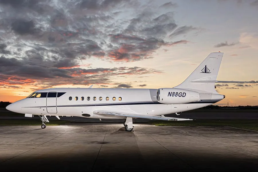 A white Dassault Falcon business jet with registration N88GD is parked on a tarmac at sunset.