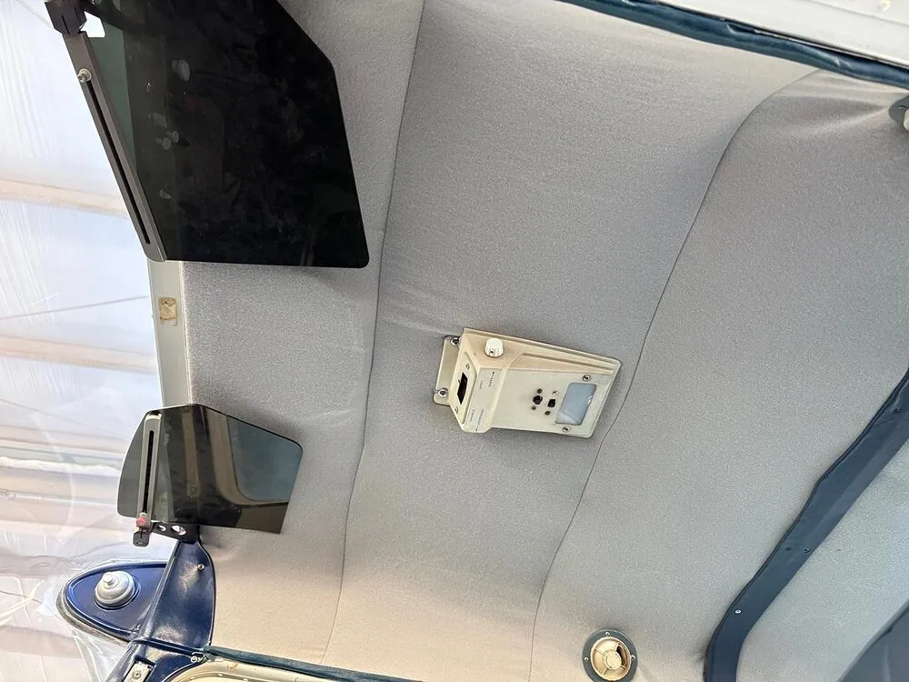 The light gray ceiling of an aircraft cabin with an overhead light and sun visors.