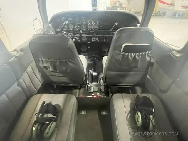The front cabin interior of a small aircraft, showing two grey pilot seats and the instrument panel.