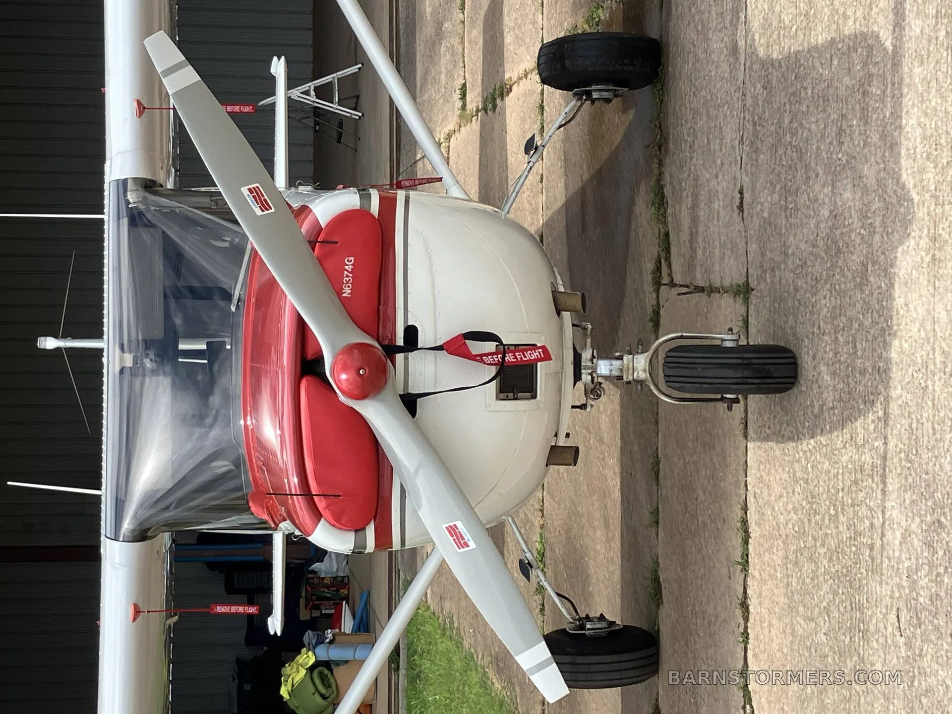 A close-up, top-down view of the front of a white and red single-engine aircraft with registration N6374G, showing the propeller and nose gear.