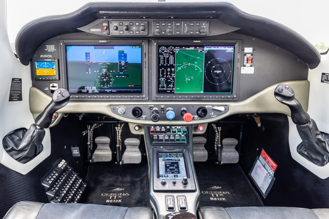 The cockpit of a Cessna TTX aircraft, featuring multiple digital display screens and a central control panel.