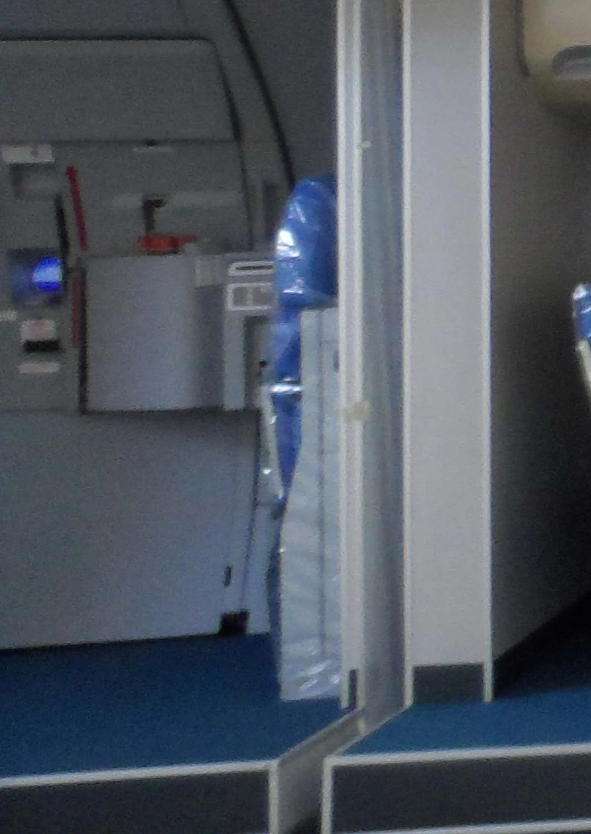 A close-up view of a blue wrapped aircraft seat and blue carpet inside a cabin.