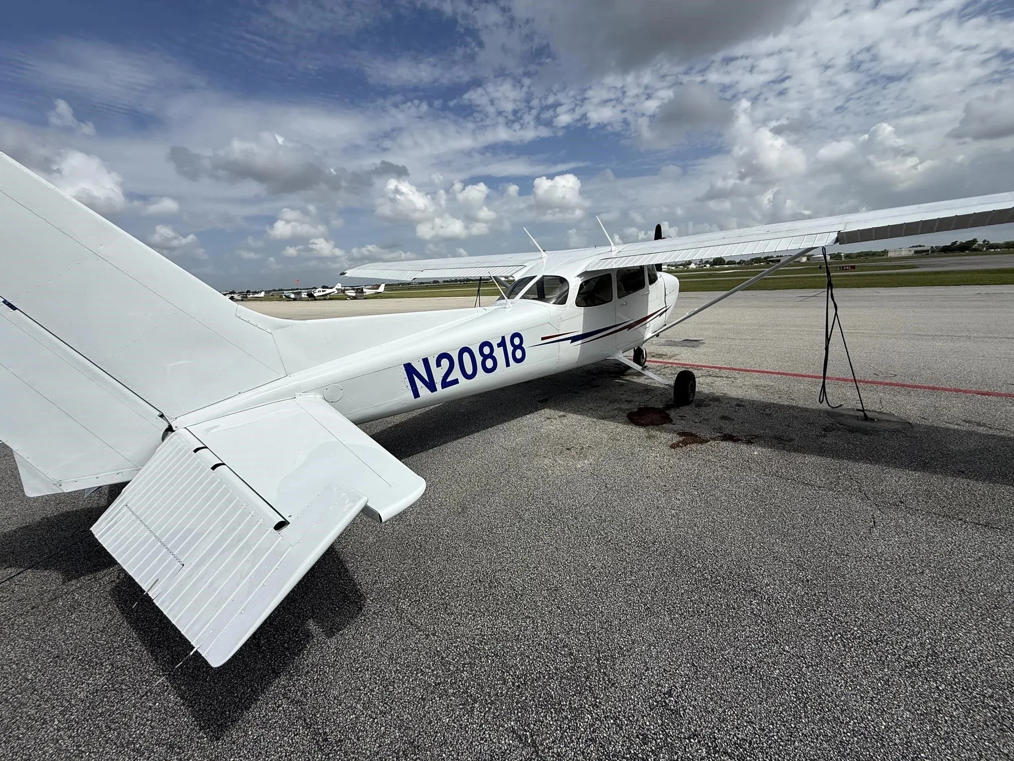 A rear-left view of the white Cessna 172 (N20818) parked on an airport tarmac.