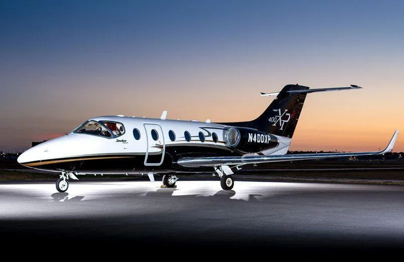 A Learjet 400XP with a black and white paint scheme, registration N400XP, parked on a tarmac at sunset.