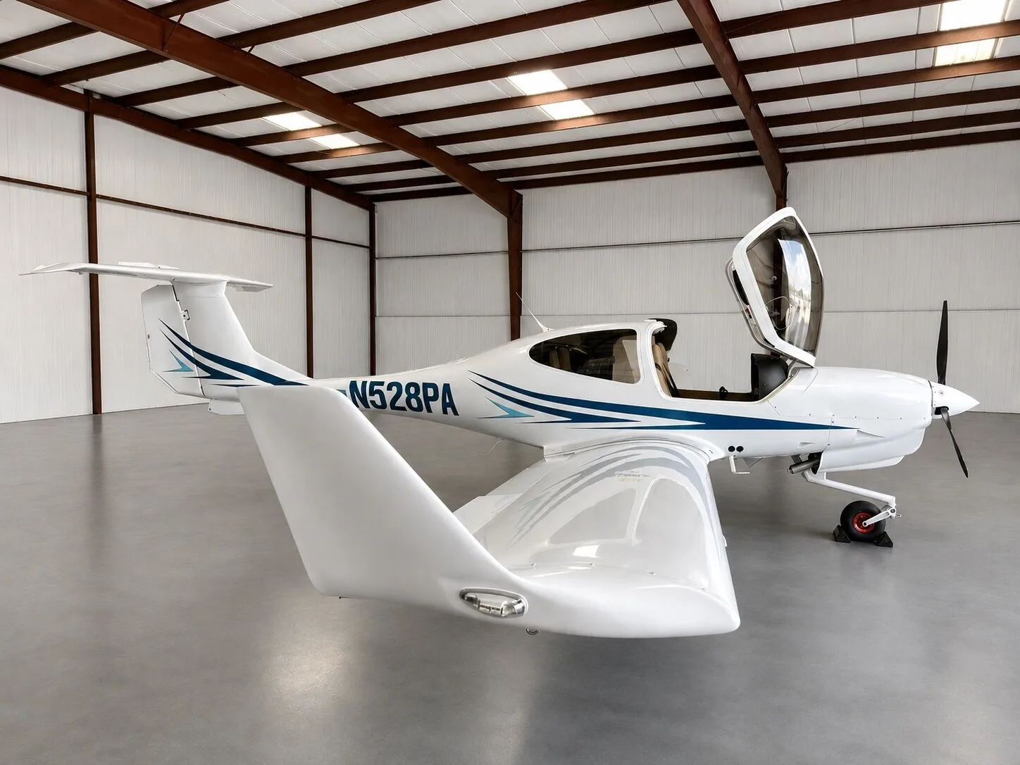 A white Diamond DA40 aircraft with blue and light blue stripes, registration N528PA, parked in a hangar with its canopy open.