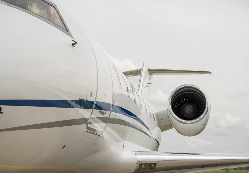 A white Bombardier Challenger business jet with blue and grey stripes parked on the tarmac.