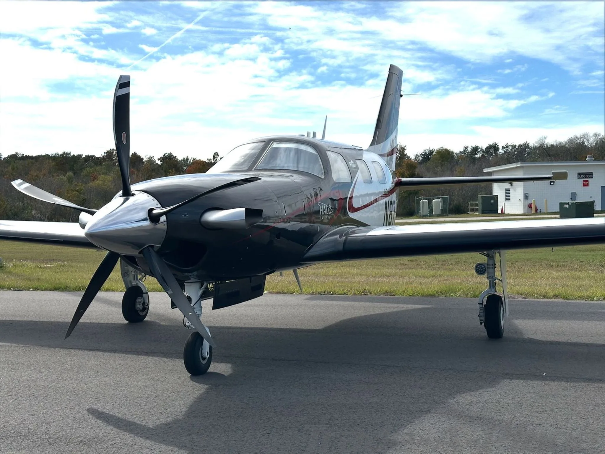 A front-quarter view of the Piper M600/SLS aircraft N87SL, showing its black and white paint scheme and propeller, parked on an airfield.