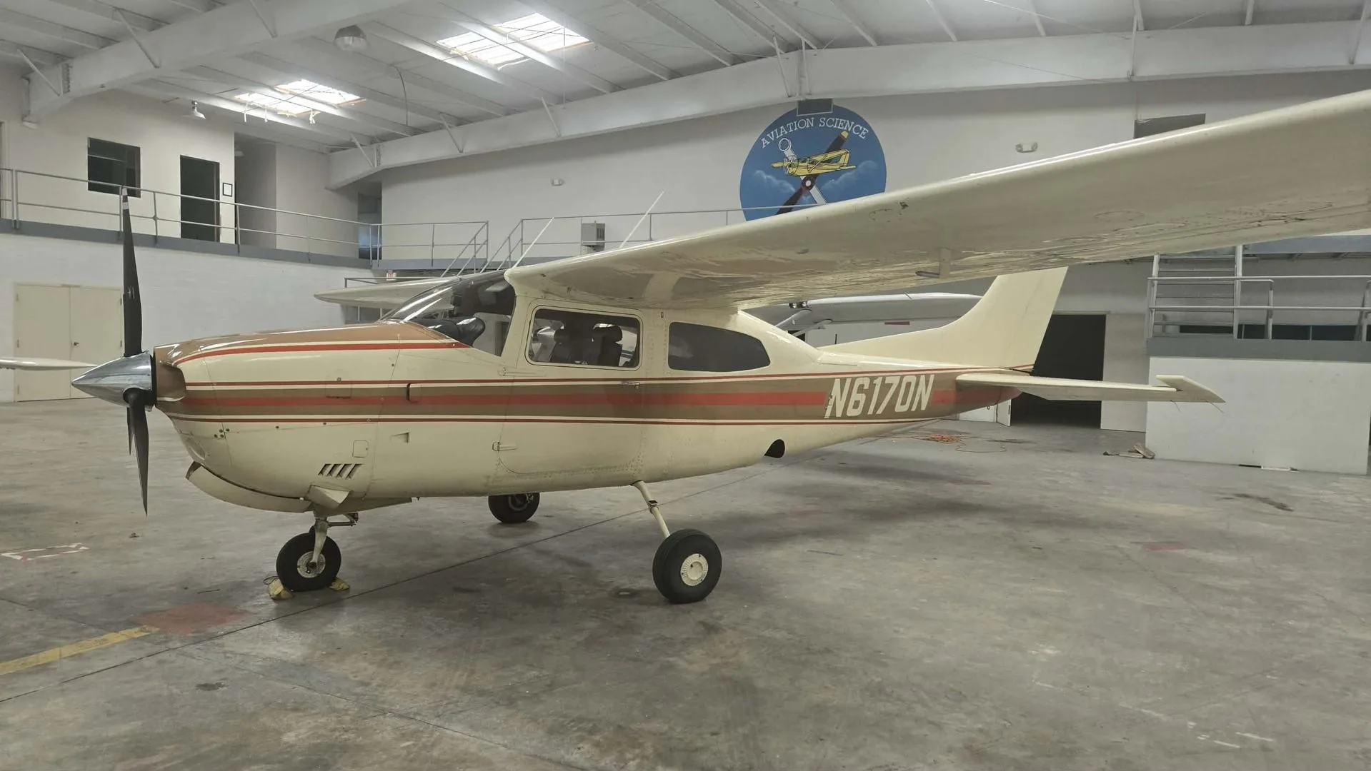 A white and brown Cessna 172 aircraft, registration N6170N, parked in a hangar.