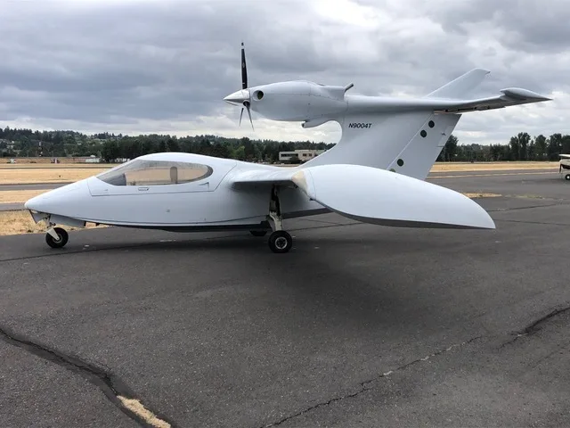 A white Searey amphibian aircraft, N9004T, is parked on an asphalt runway under a cloudy sky.