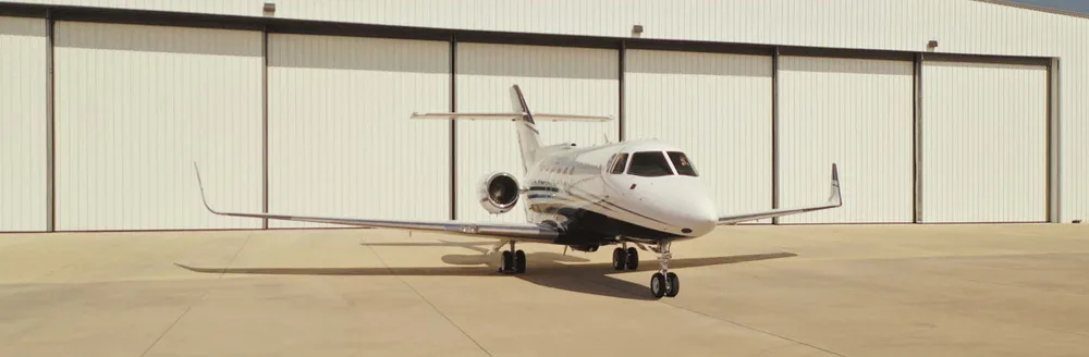 A white and blue Hawker 800XP business jet, registration N800AF, parked head-on in front of a large white hangar.