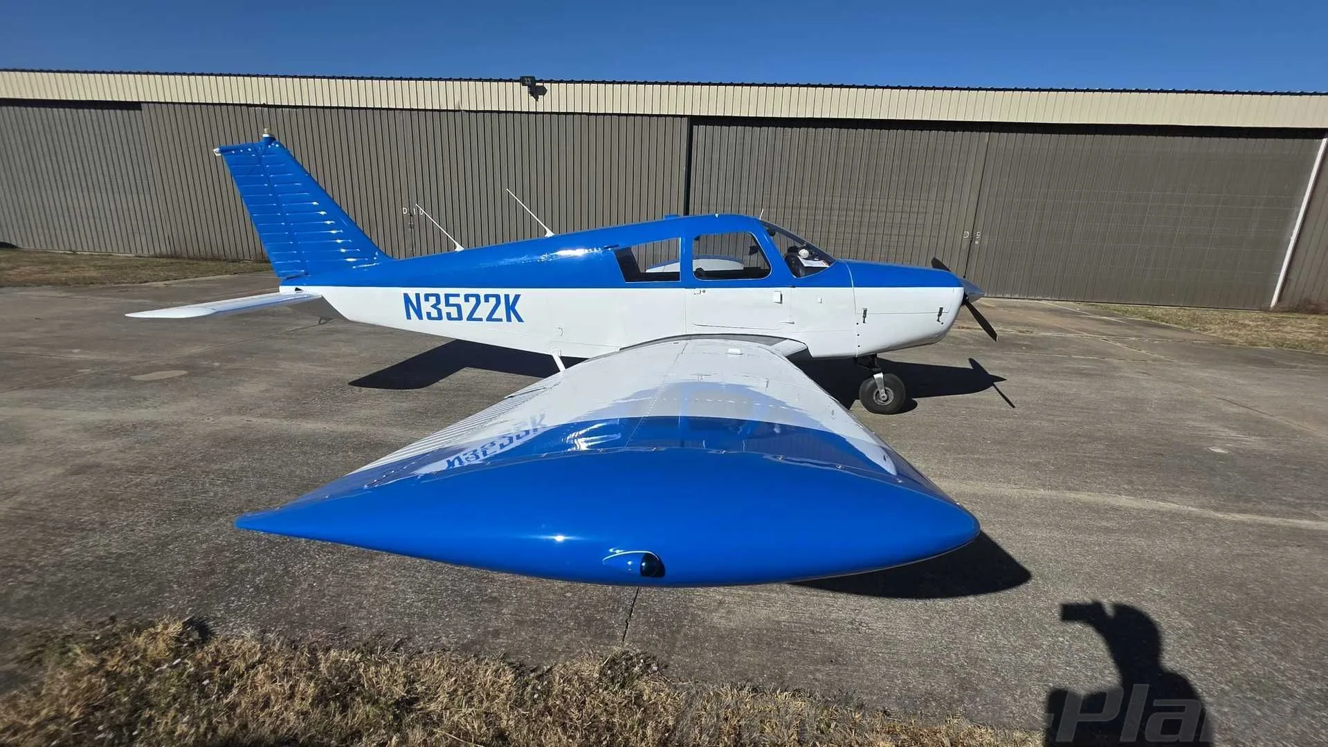 A front-side view of the blue and white single-engine aircraft, N3522K, parked on an asphalt ramp.