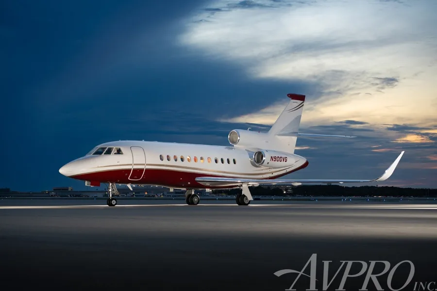 A Dassault Falcon 900LX, registration N900VG, parked on the tarmac at dusk with a white and red paint scheme.