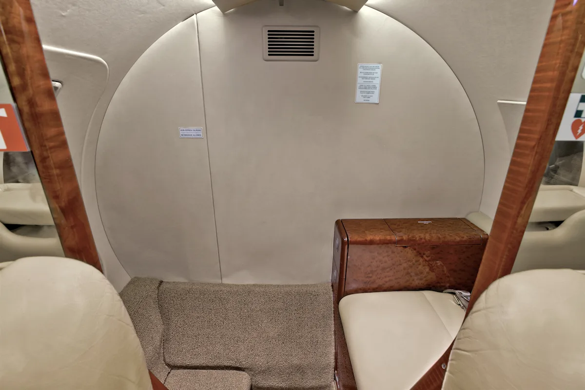 Aircraft interior showing the rear of the cabin with a wood cabinet.