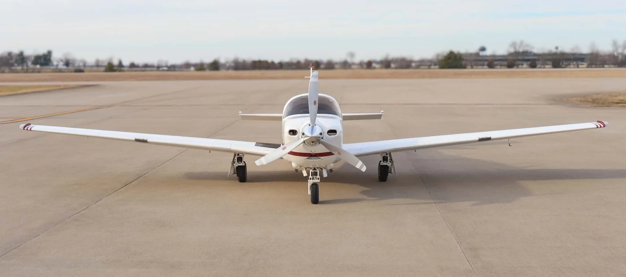 Head-on view of a white and red single-engine propeller aircraft, N993JT, on an airfield.