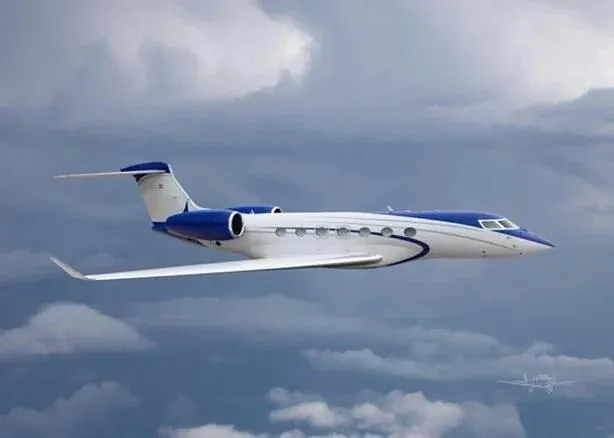 A white and blue business jet flies through a cloudy sky, seen from the side.