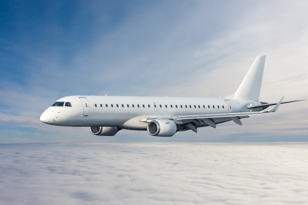A white jet flying above a layer of clouds.