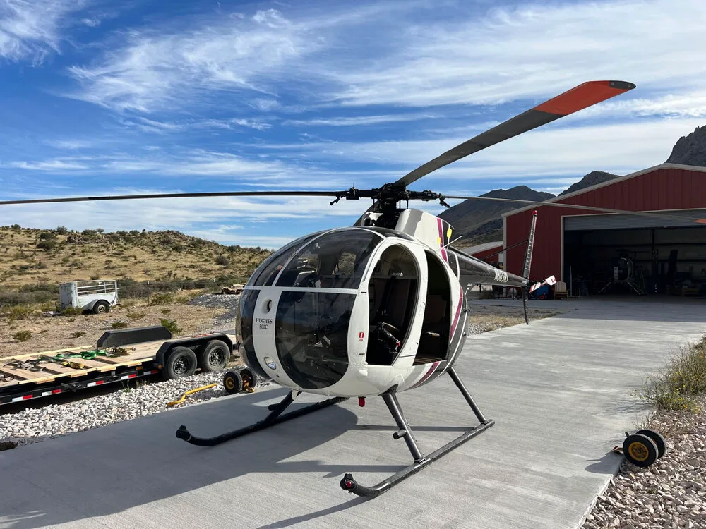 A McDonnell Douglas 500C helicopter parked on a concrete surface.