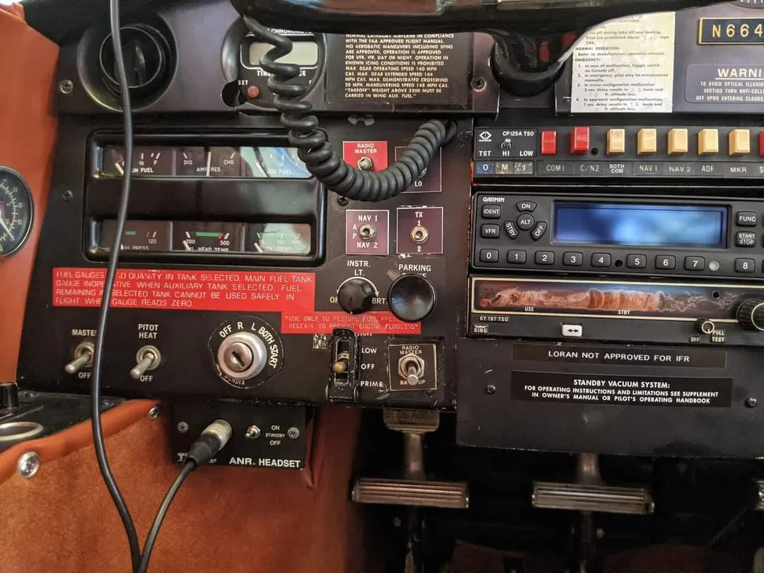 A close-up of the lower left side of the Bellanca cockpit, showing fuel gauges, switches, and headset jacks.