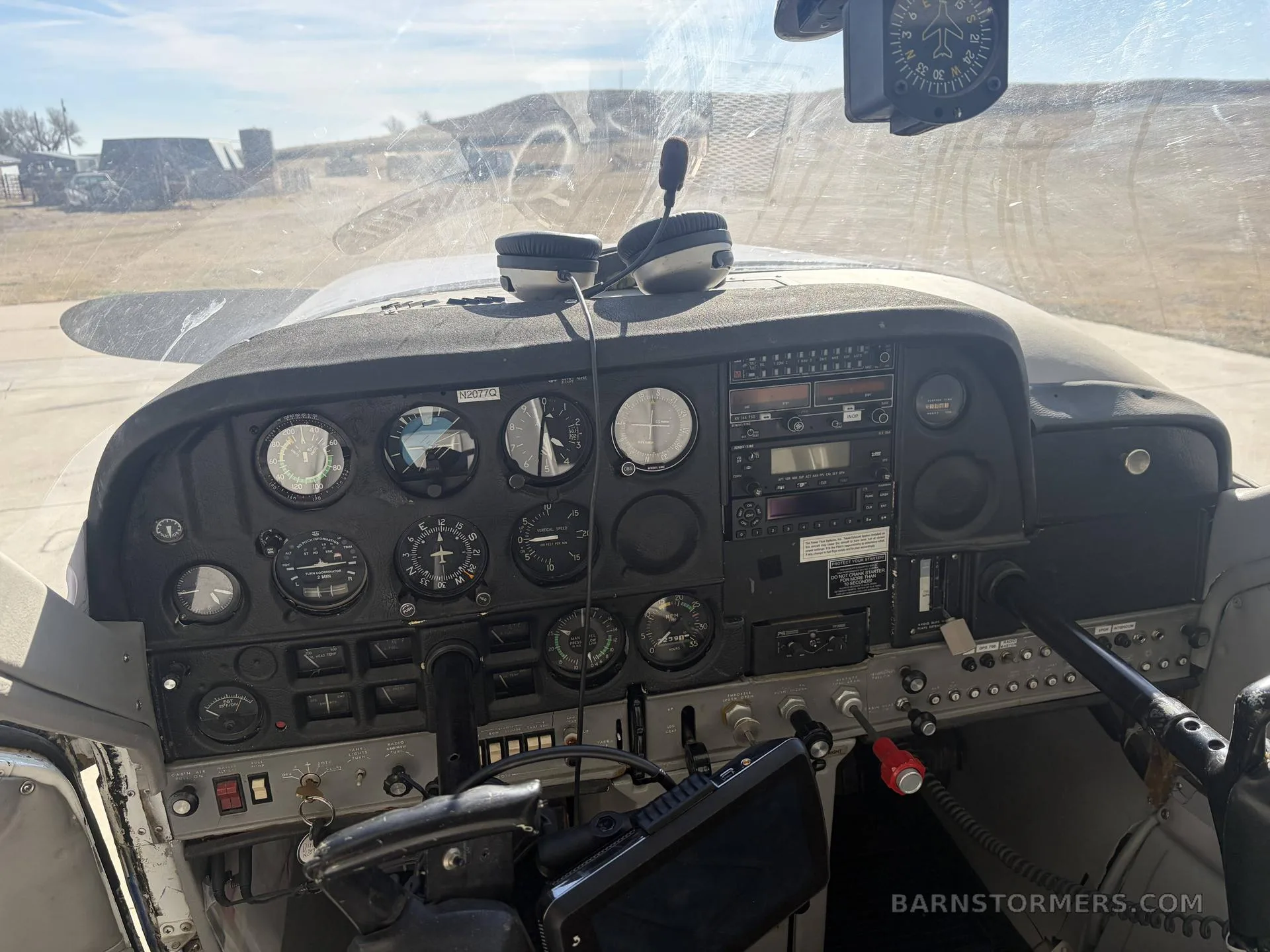 The instrument panel of the aircraft, featuring various gauges, radios, and controls, with a headset on the glare shield.