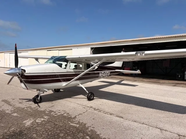 A front-left view of a white and maroon Cessna 182 Skylane (N9410X) parked on an airfield.