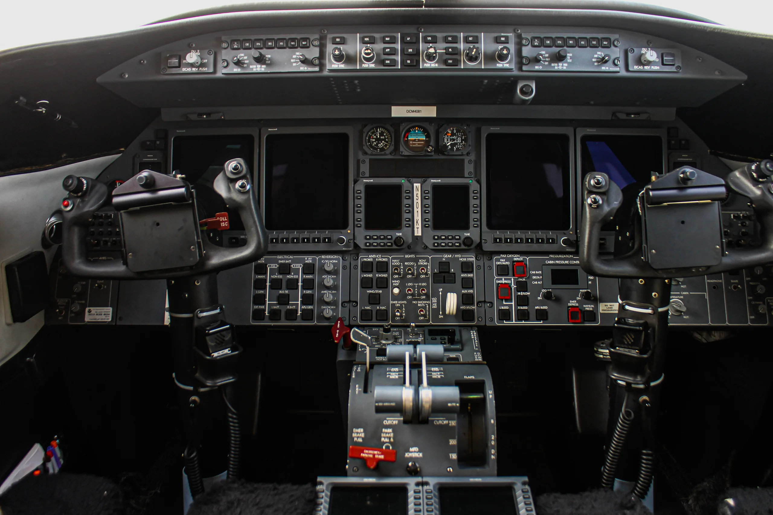 The cockpit instrument panel of a business jet with multiple display screens and controls.