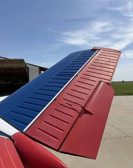A close-up view of the aircraft's tail, featuring a blue horizontal stabilizer and red elevator.