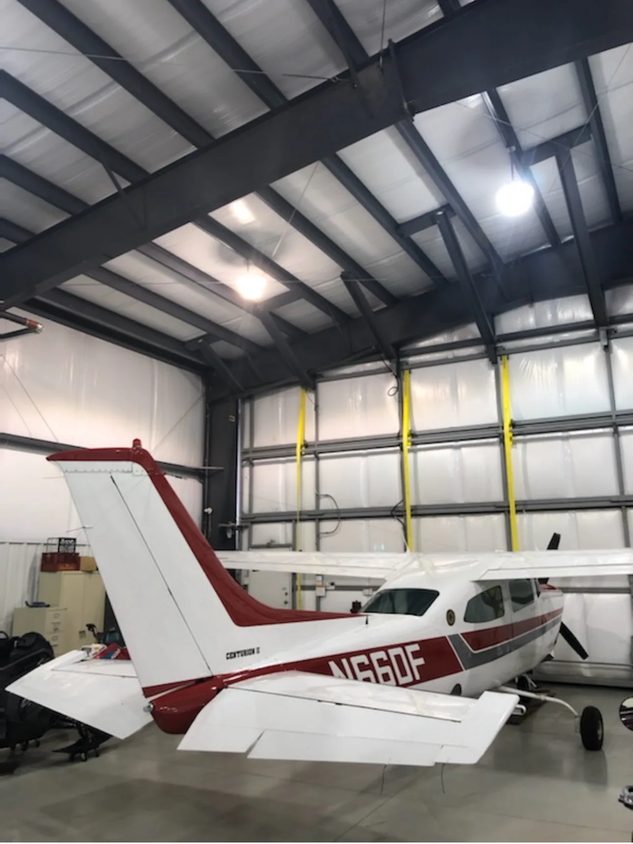 Rear-side view of a white and red Cessna Centurion II aircraft N66DF in a hangar.