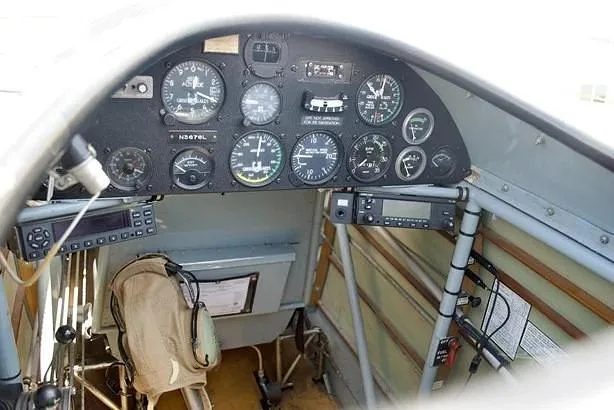 A close-up view of the instrument panel in the cockpit of a biplane, showing gauges and radios.