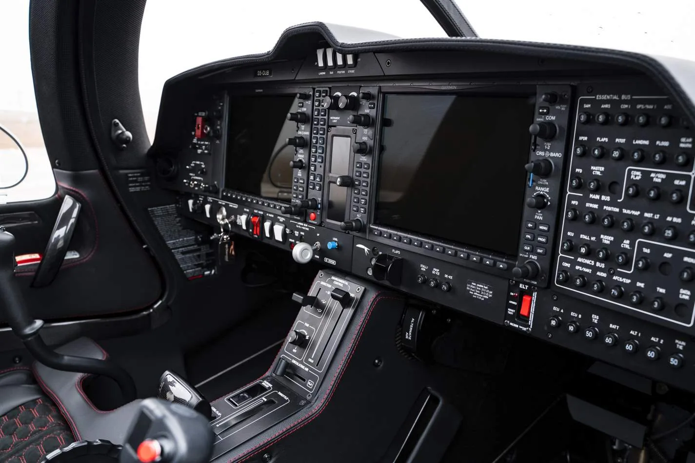 The modern cockpit of an aircraft, featuring large digital displays and numerous control buttons.