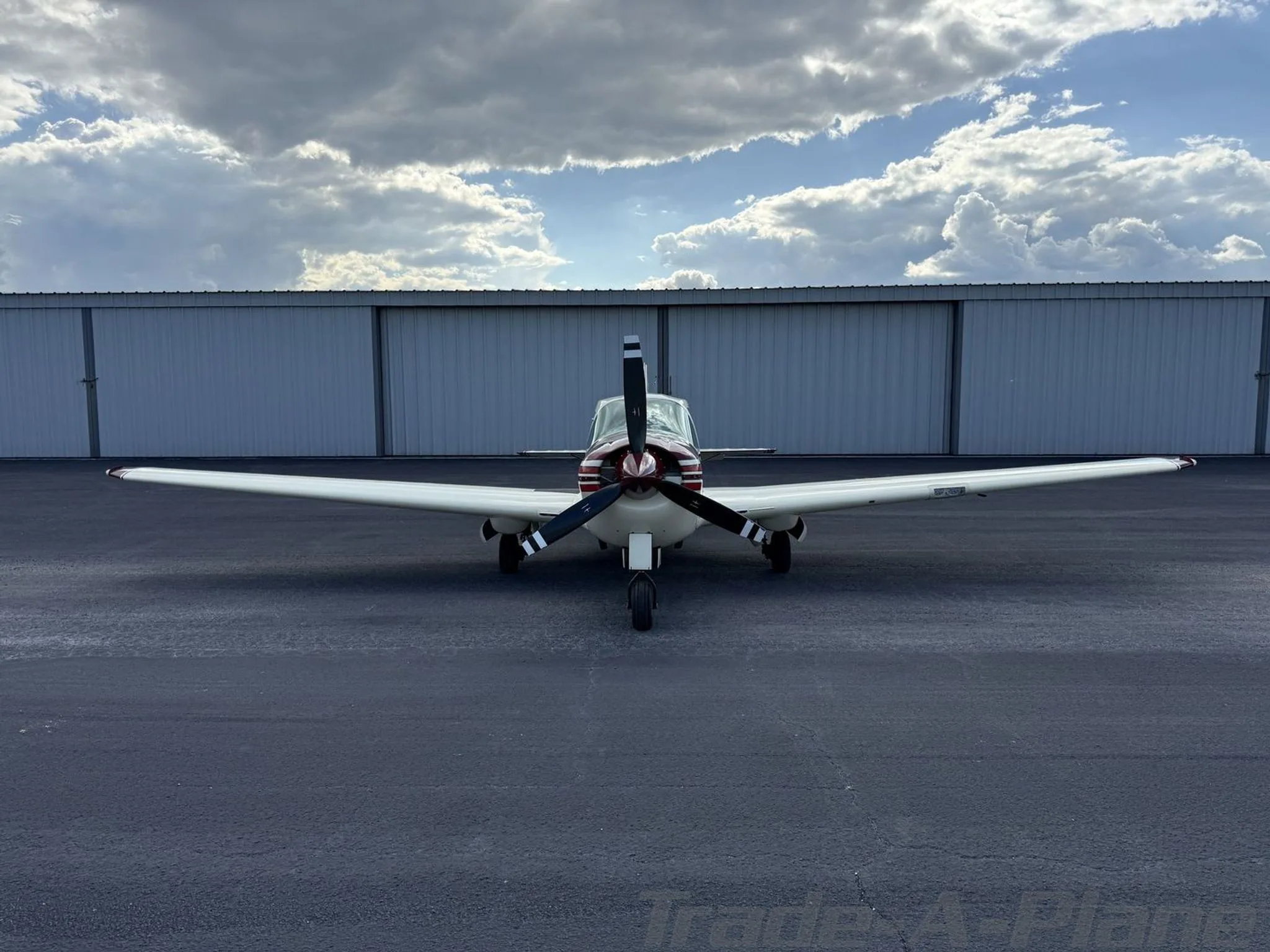Front view of a white and maroon Bellanca Viking N63083 parked on a tarmac.