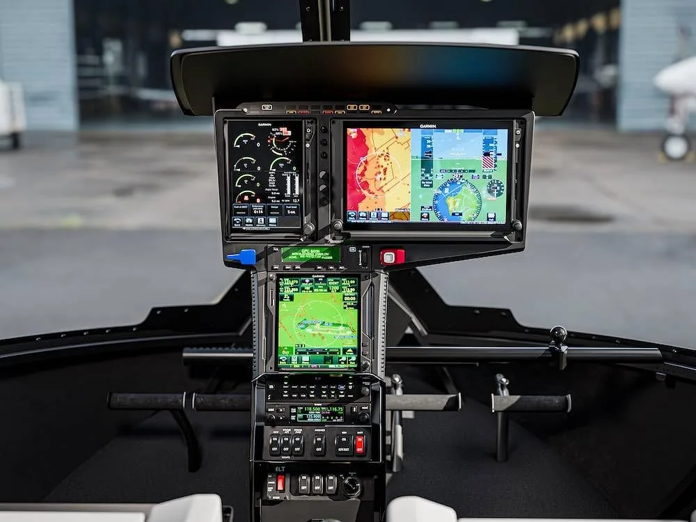 The cockpit of a helicopter showing multiple Garmin display screens and controls.