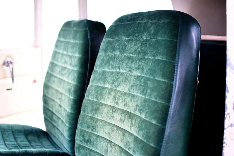 Two plush dark green velvet aircraft seats with horizontal stitching.