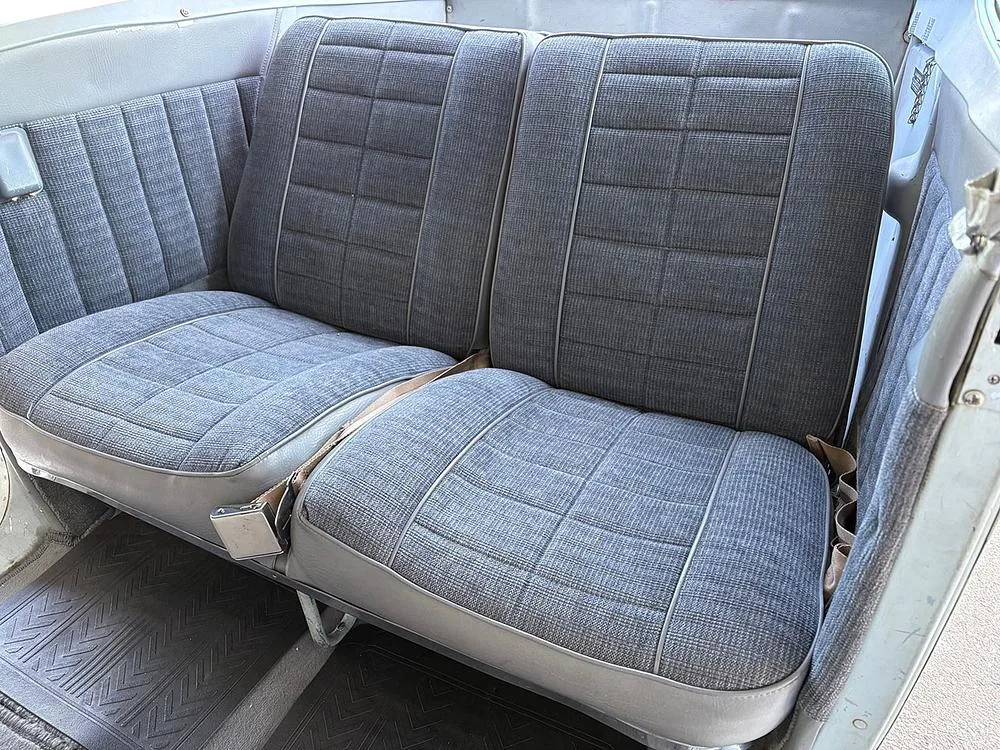 The rear cabin seats of an aircraft, upholstered in gray fabric with a checkered pattern.