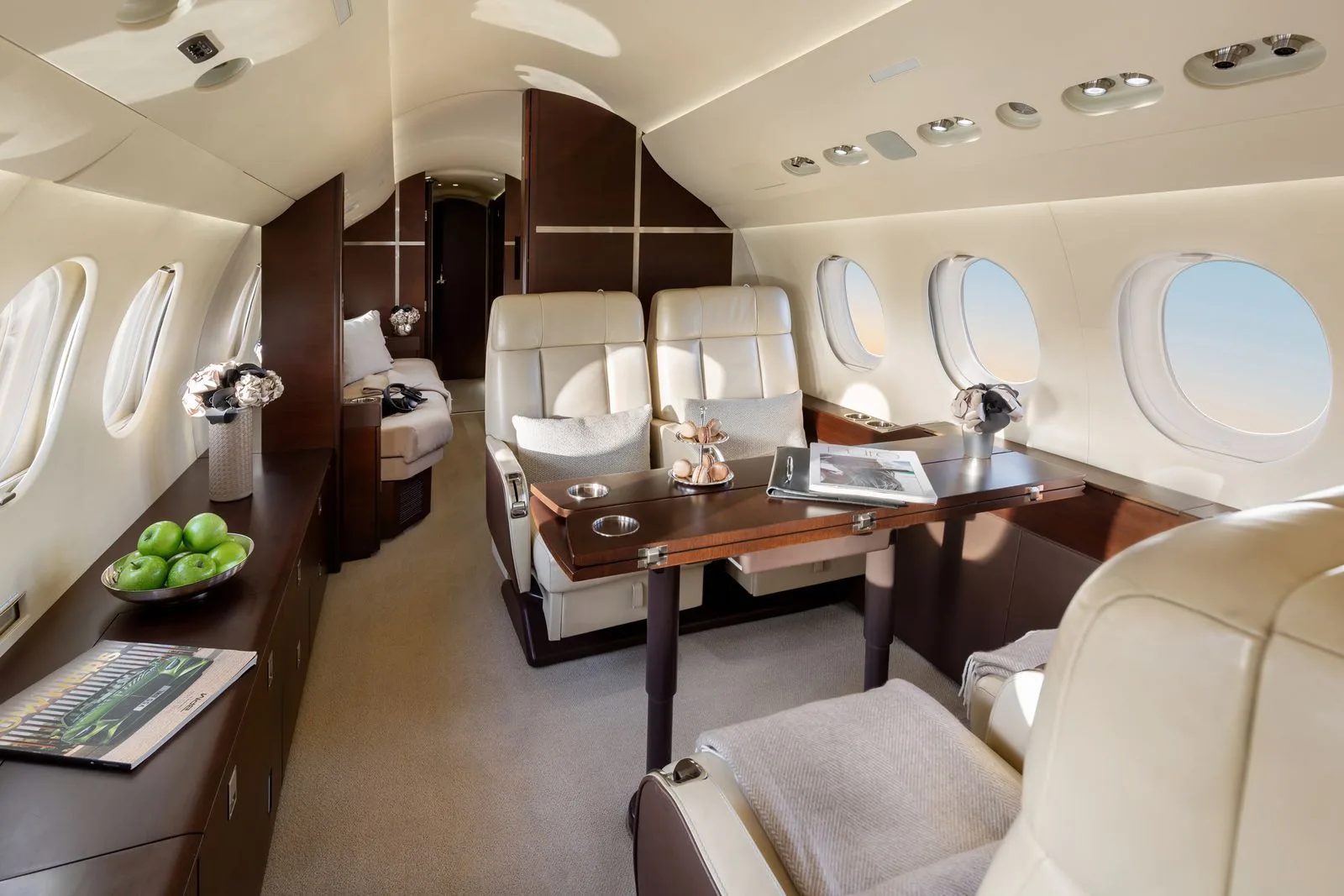 A view of the interior of a Falcon jet with leather seats and a table.
