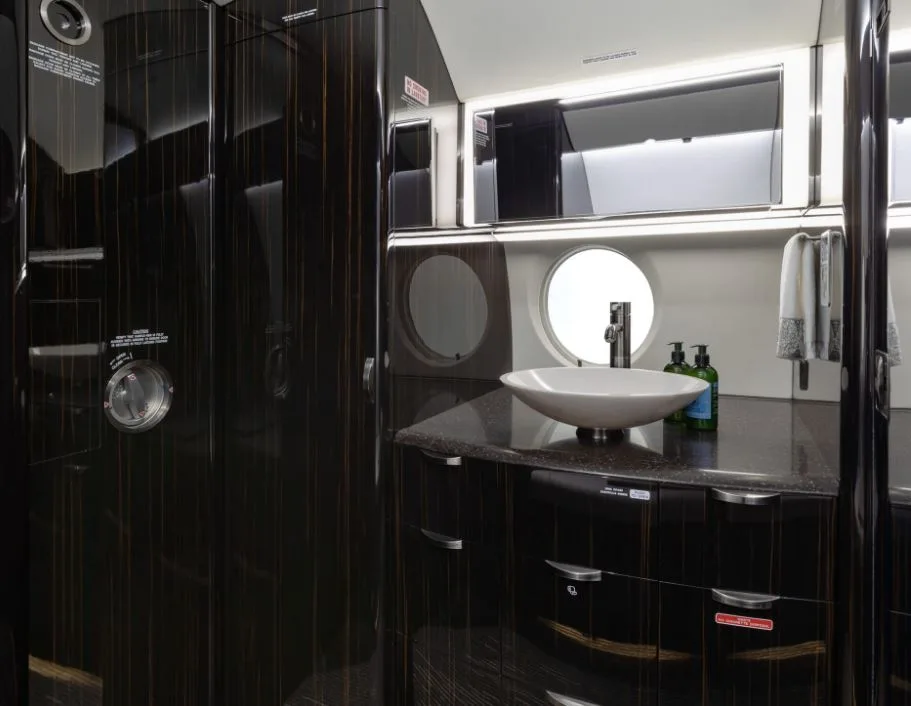 Aircraft lavatory with sink and dark wood cabinetry.