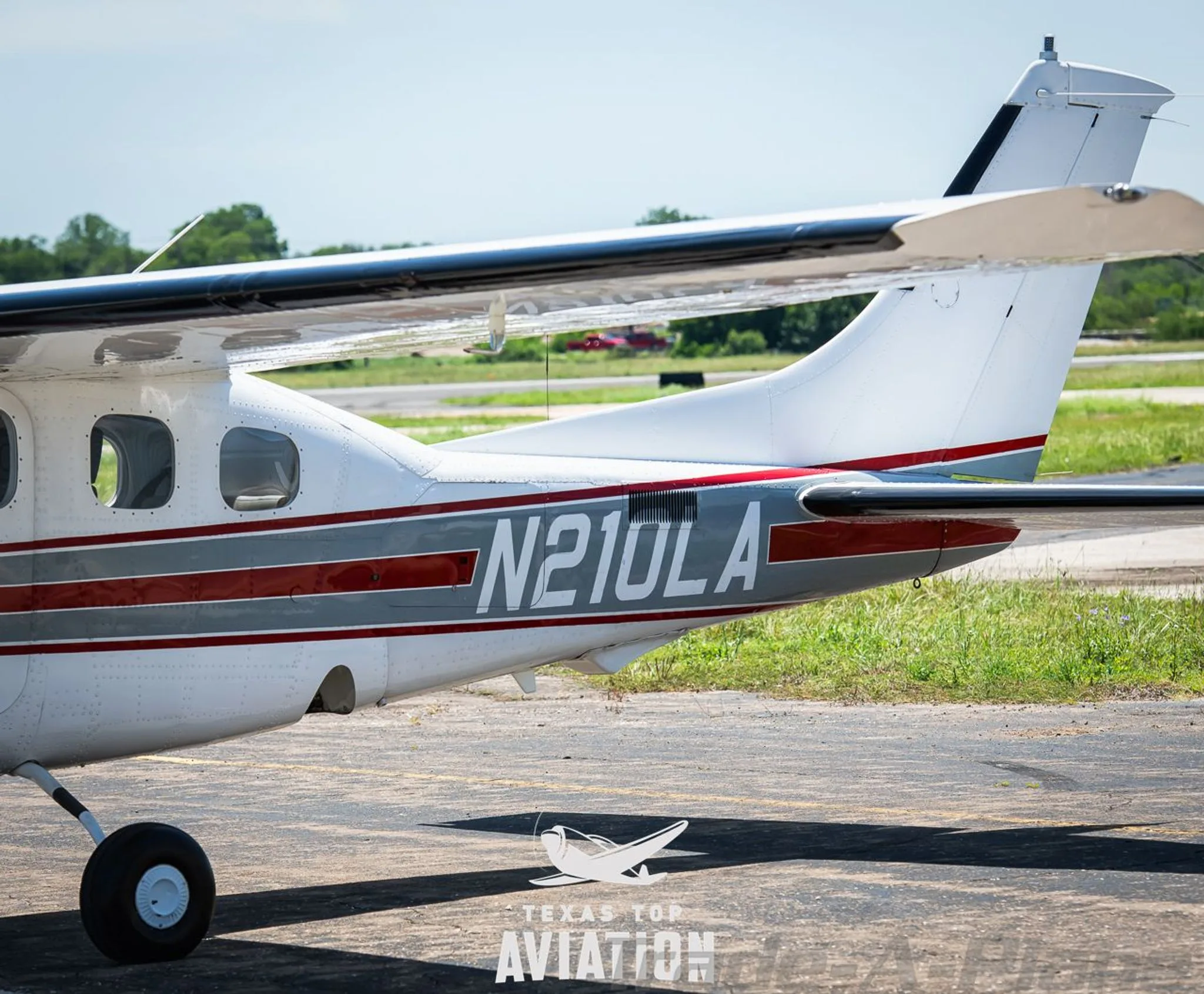 A close-up of the tail section of a white Cessna 210 Centurion (N210LA), showing the registration number.
