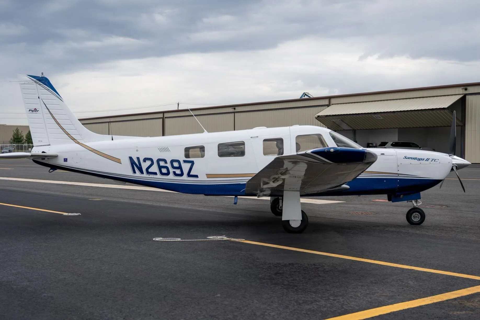 A white Piper Saratoga II TC aircraft with blue and gold stripes, tail number N269Z, parked on an airport tarmac.