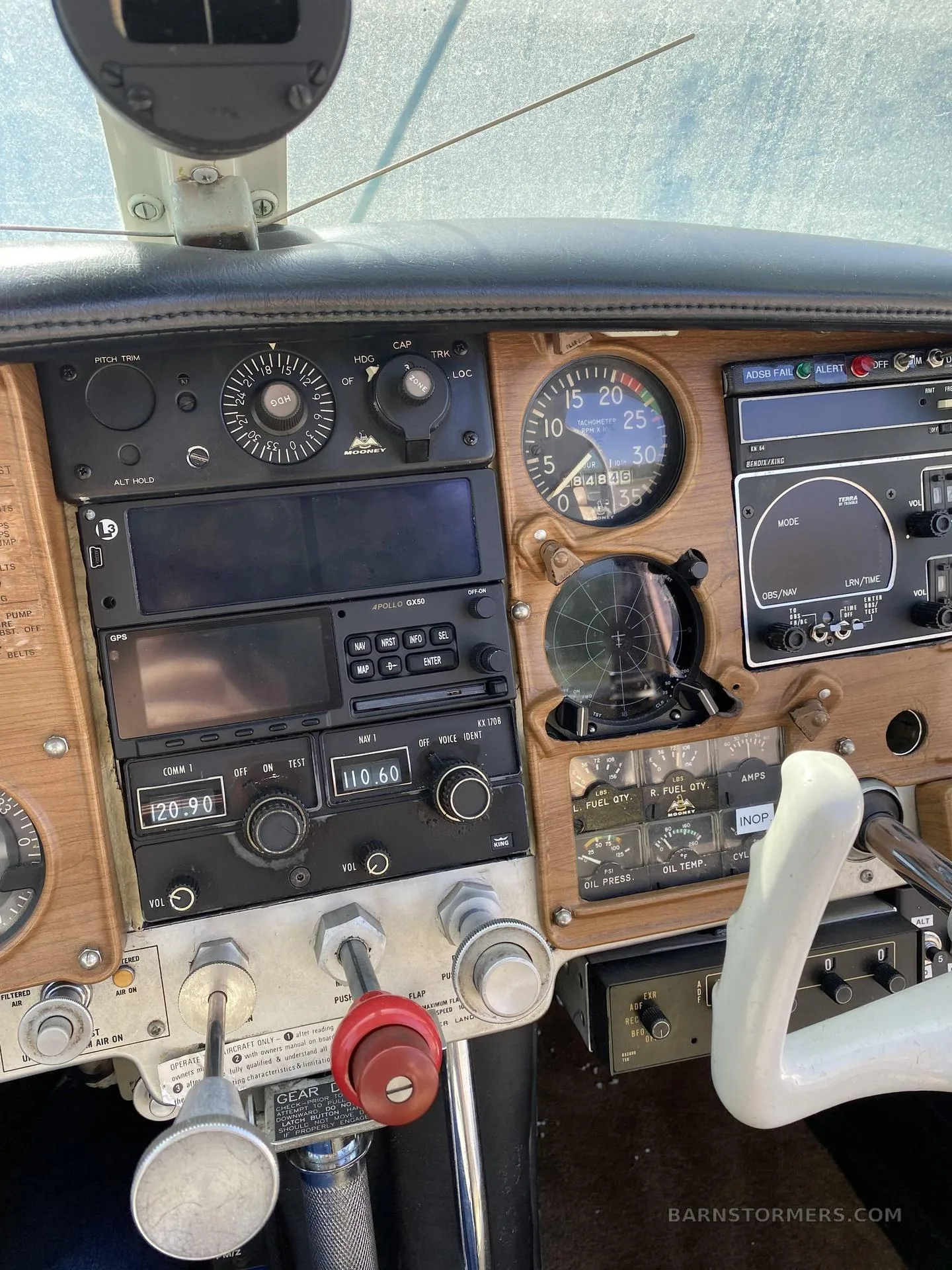Close-up view of the aircraft's instrument panel with various gauges, radios, and a wooden-look finish.