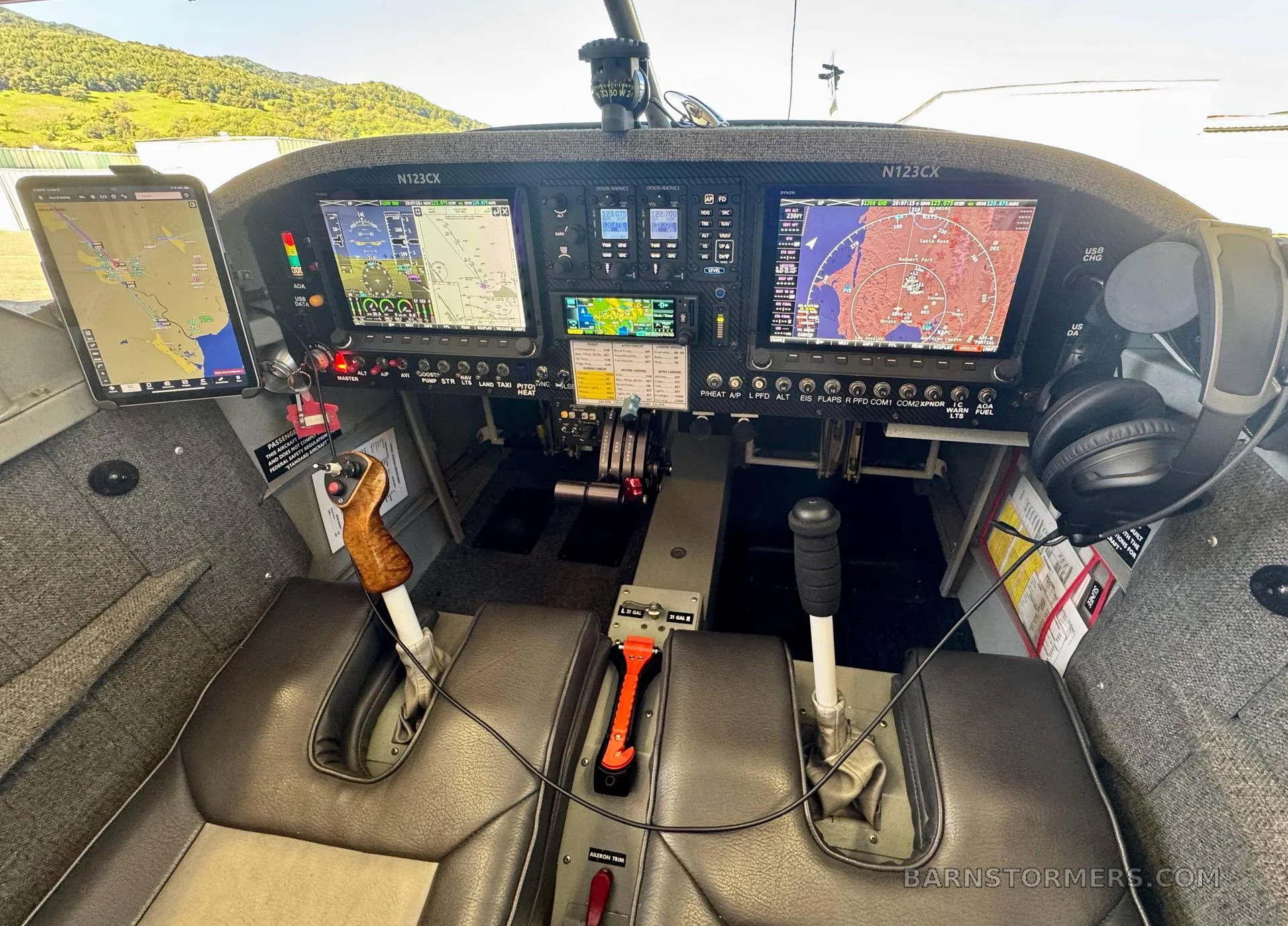 The cockpit of a small aircraft, showing multiple digital displays, controls, and two seats.