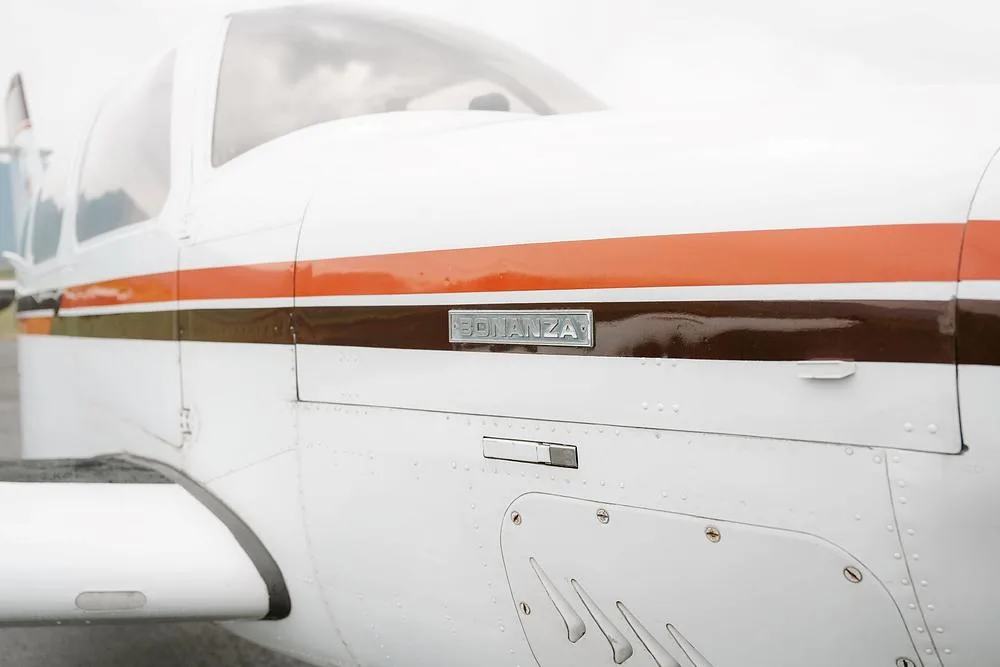 A very close-up view of the "BONANZA" nameplate and the brown and orange stripe on the aircraft's fuselage.