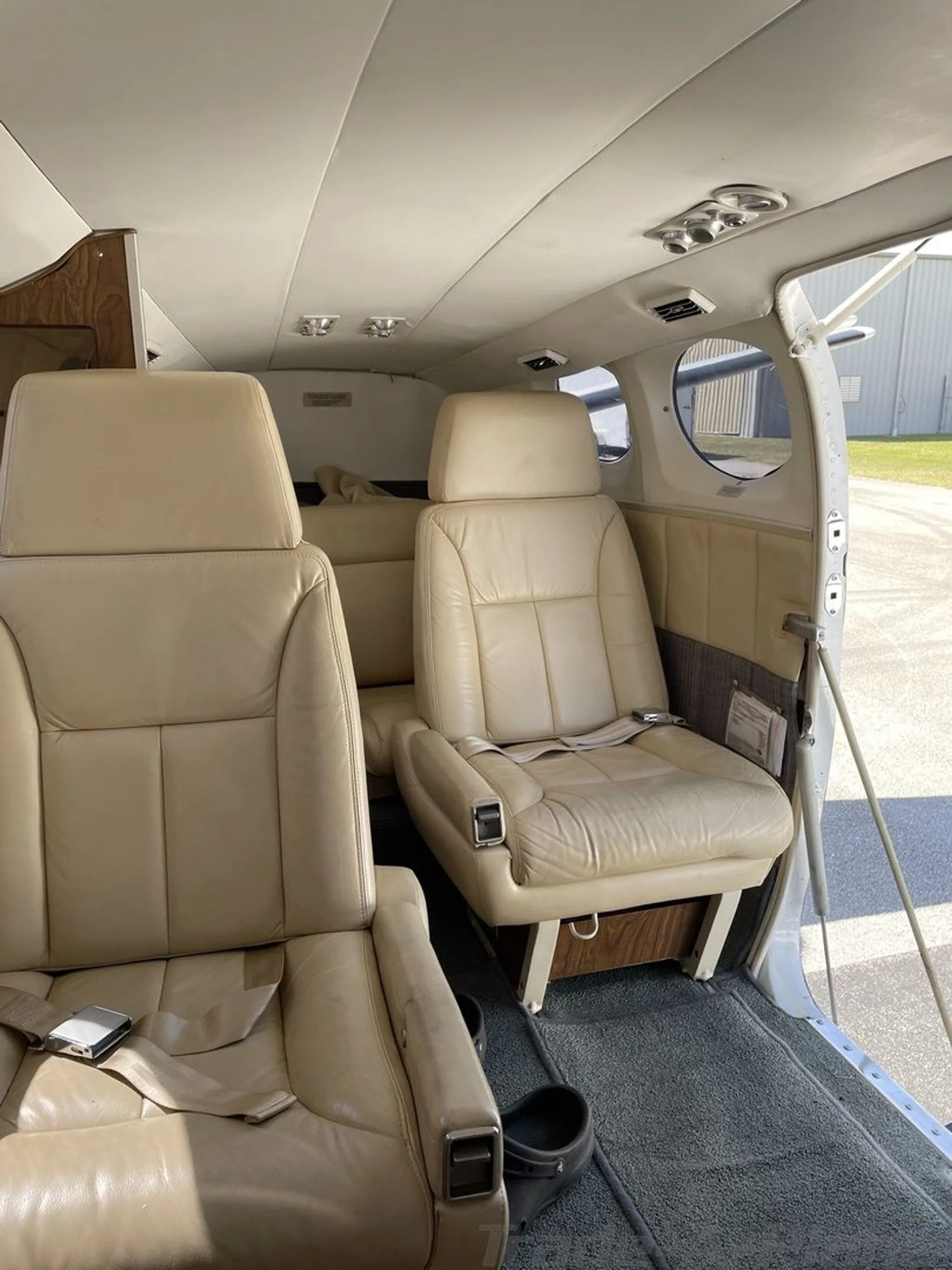 The interior cabin of the aircraft, showing beige leather passenger seats and an open rear door.