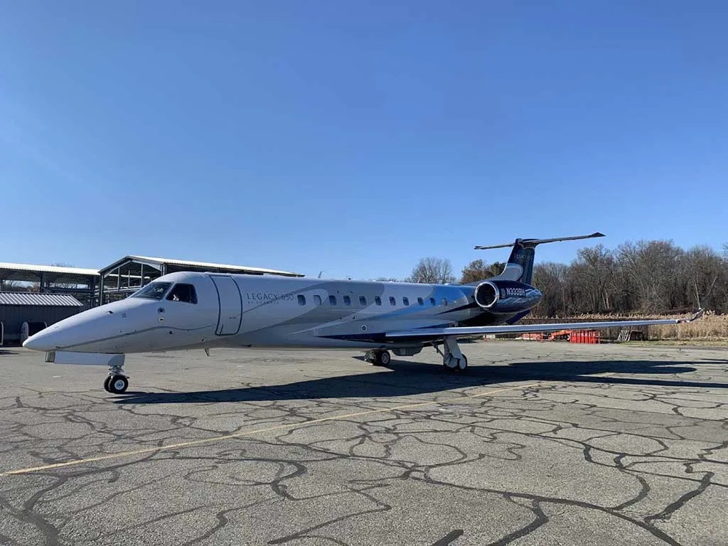 The Embraer Legacy 650 (N333BH) with its blue and white paint scheme parked on a sunny tarmac.