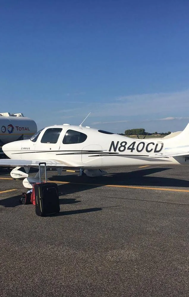 A white Cirrus SR22 aircraft with registration N840CD and black and tan stripes is parked on an airport tarmac.