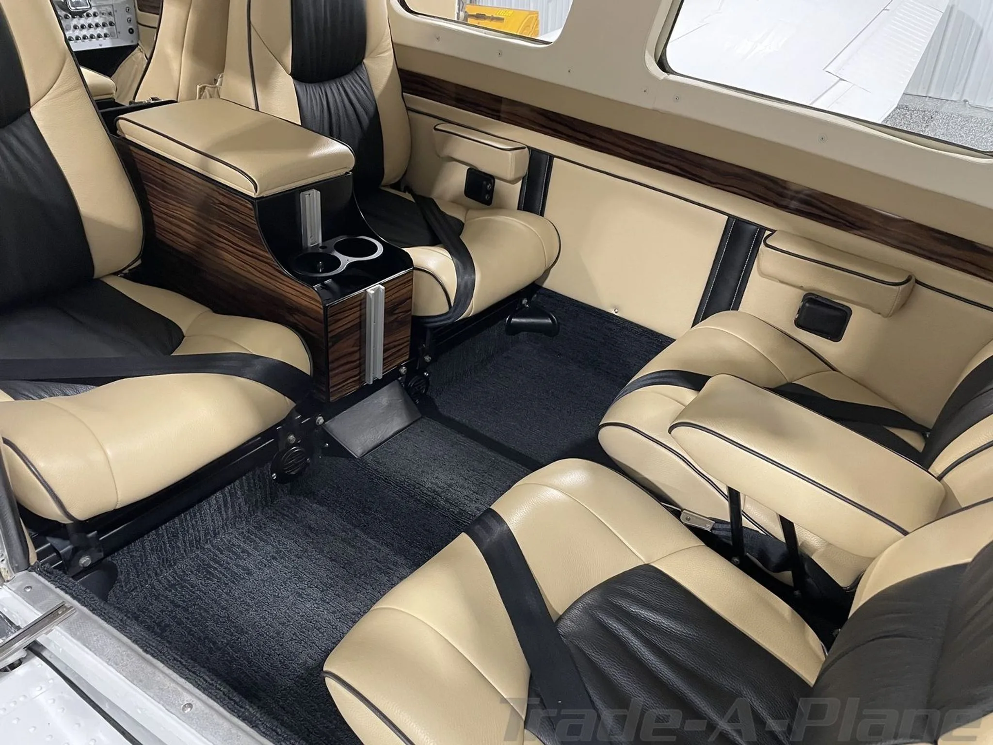 A view of the rear tan and black leather cabin seats and wood-trimmed console in a Piper Saratoga.